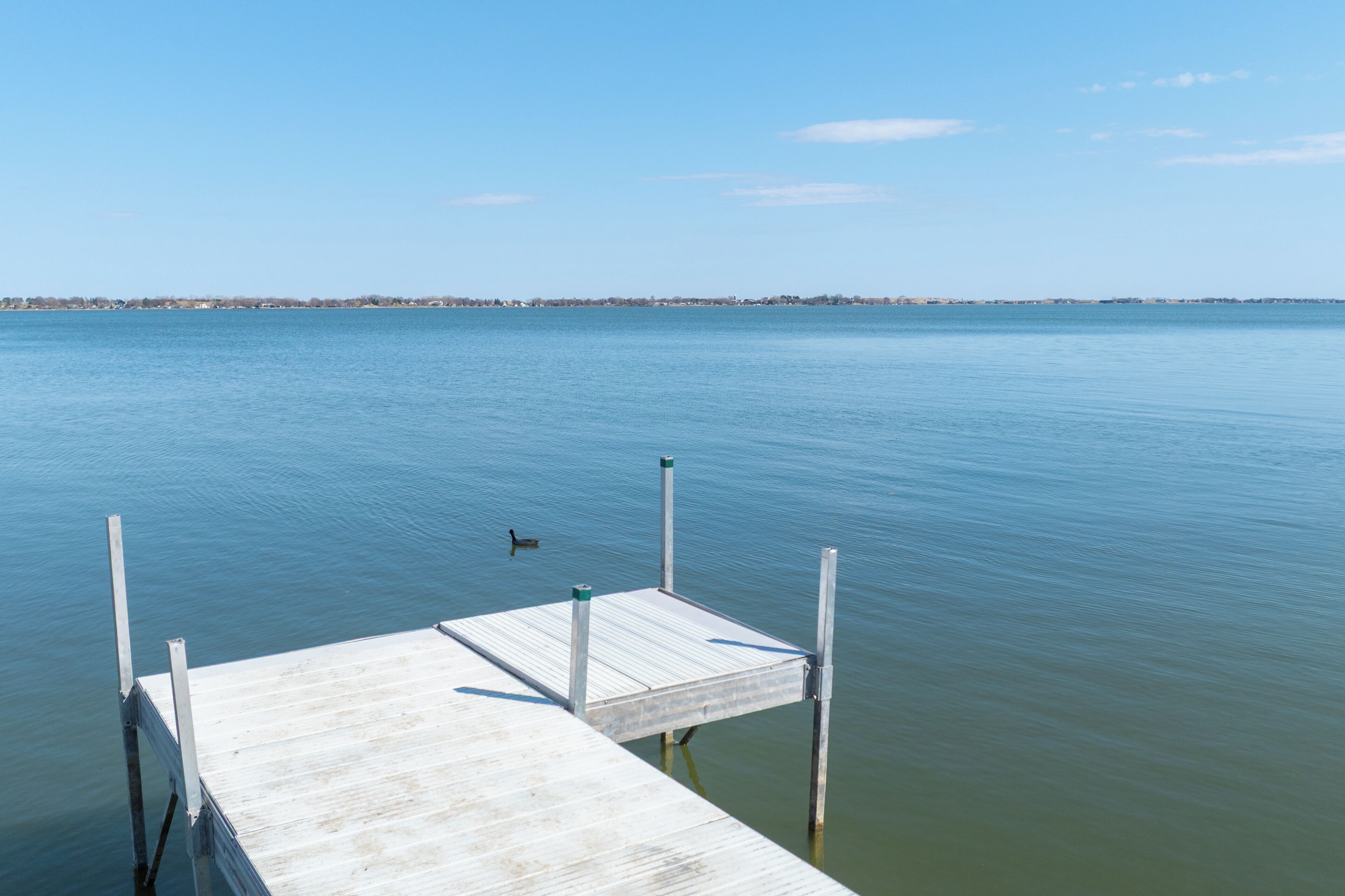 A wooden dock extending into calm water with a distant shoreline.