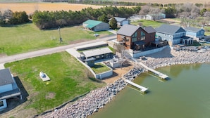 A lakeside property with a large house, a dock, and a grassy area. - Private Sauna, Hot Tub, Beach Lake Poinsett (Lake Norden)