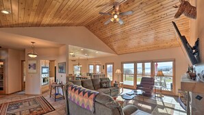 A spacious living room with a high ceiling, a large sofa, a coffee table, and a fireplace. - Lakefront Henrys Lake Cabin: w/ Mtn & Lake Views! (Island Park)