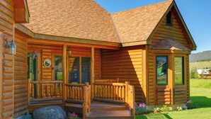 A log cabin with a wooden porch, a stone pathway, and a grassy yard. - Lakefront Henrys Lake Cabin: w/ Mtn & Lake Views! (Island Park)