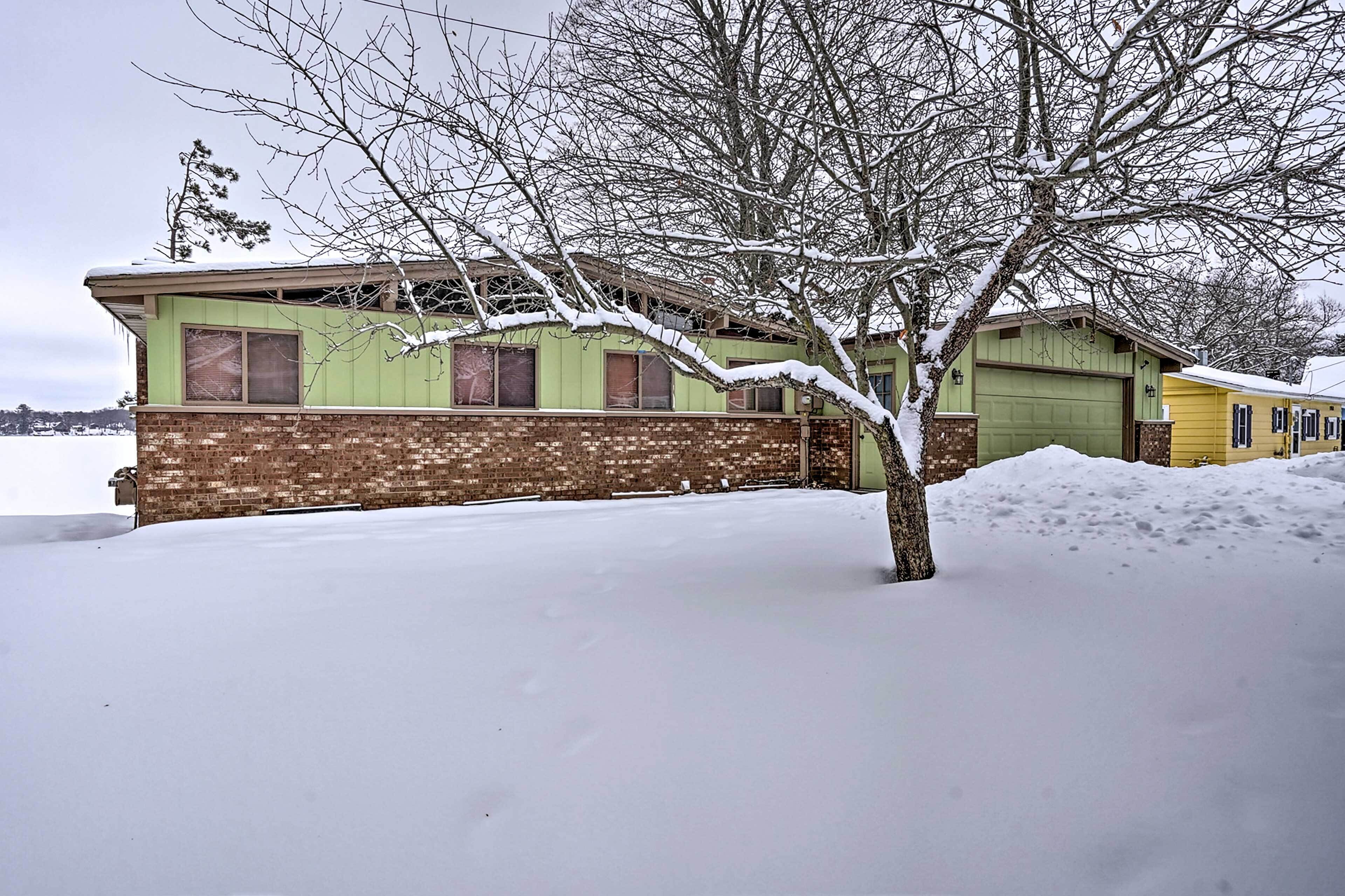 Un bâtiment à deux étages, avec une base en briques et une partie supérieure verte, entouré de neige.