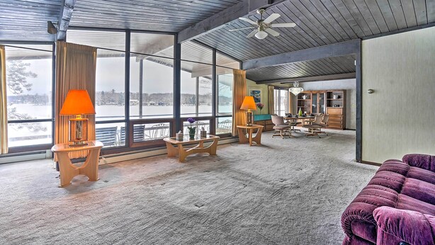A spacious living area with large windows, a ceiling fan, and a cozy seating area. - Rustic Crooked Lake Cottage w/ Views & Deck (Lake)