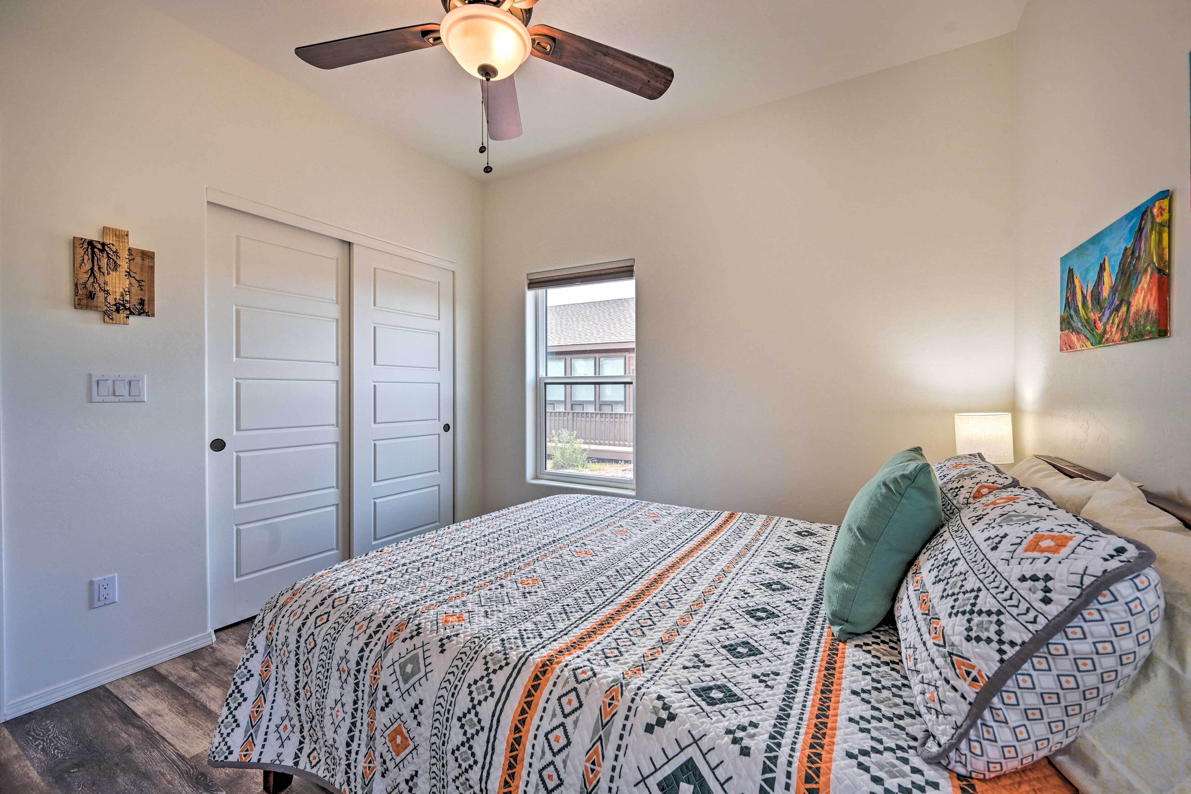 A bedroom with a bed, a ceiling fan, a window, and a door.