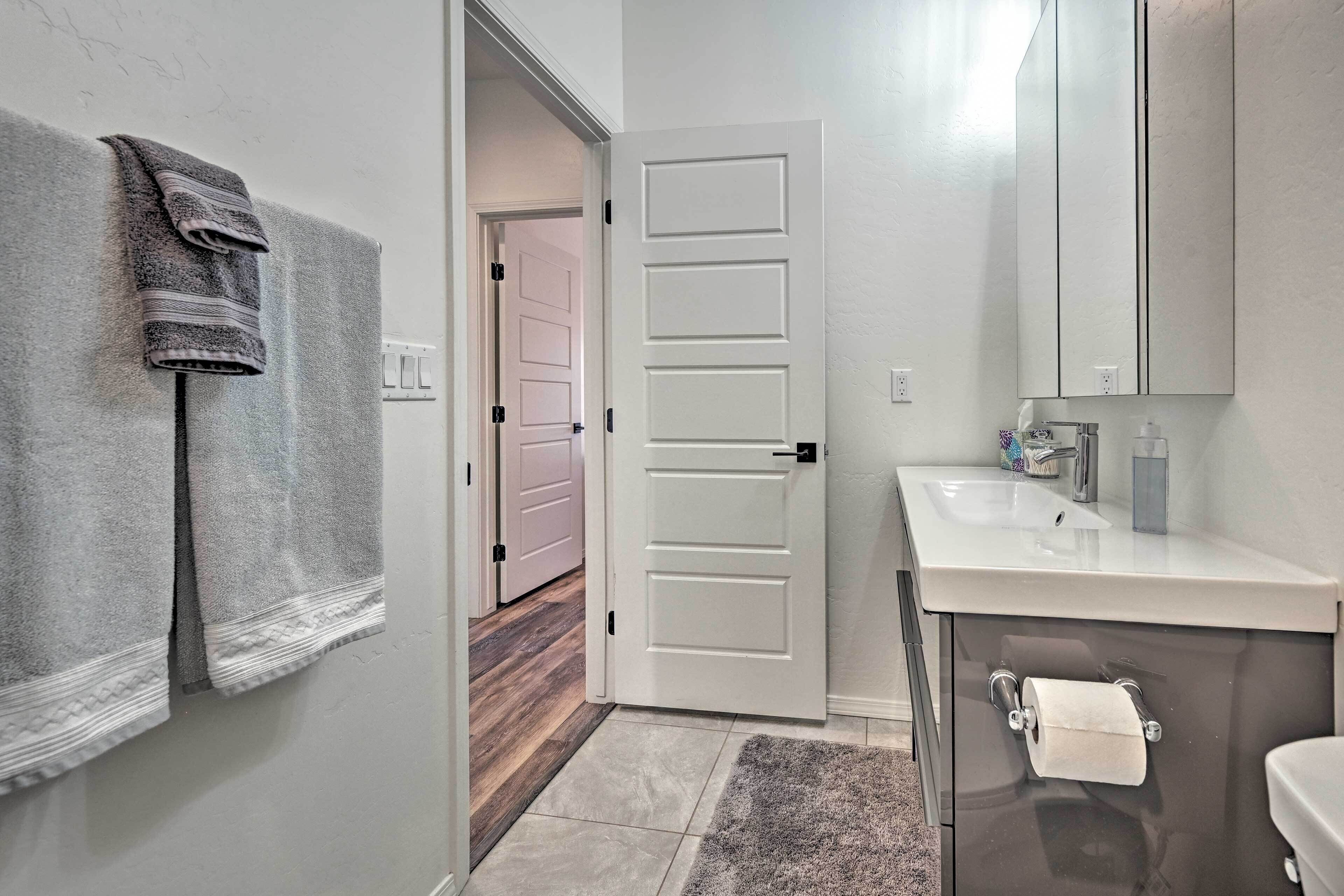 A bathroom with a white sink, a mirror, and a towel rack.