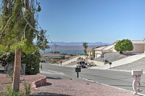Une rue résidentielle bordée de maisons, avec un camion garé et une vue dégagée sur les montagnes au loin.