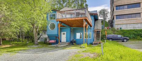 A two-story building with a balcony, a gravel driveway, and a car parked nearby.