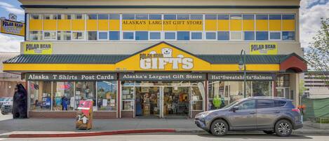 A two-story building with a yellow facade, featuring a sign that reads "Alaska's Largest Gift Store."