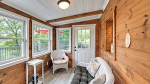 A wooden cabin interior with a white sofa, a wicker chair, and a small table. - Our Lakeside Retreat w/ Deck on Lake Herrington! (Lancaster)