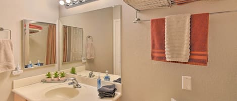 A bathroom with a sink, mirror, and towel rack.