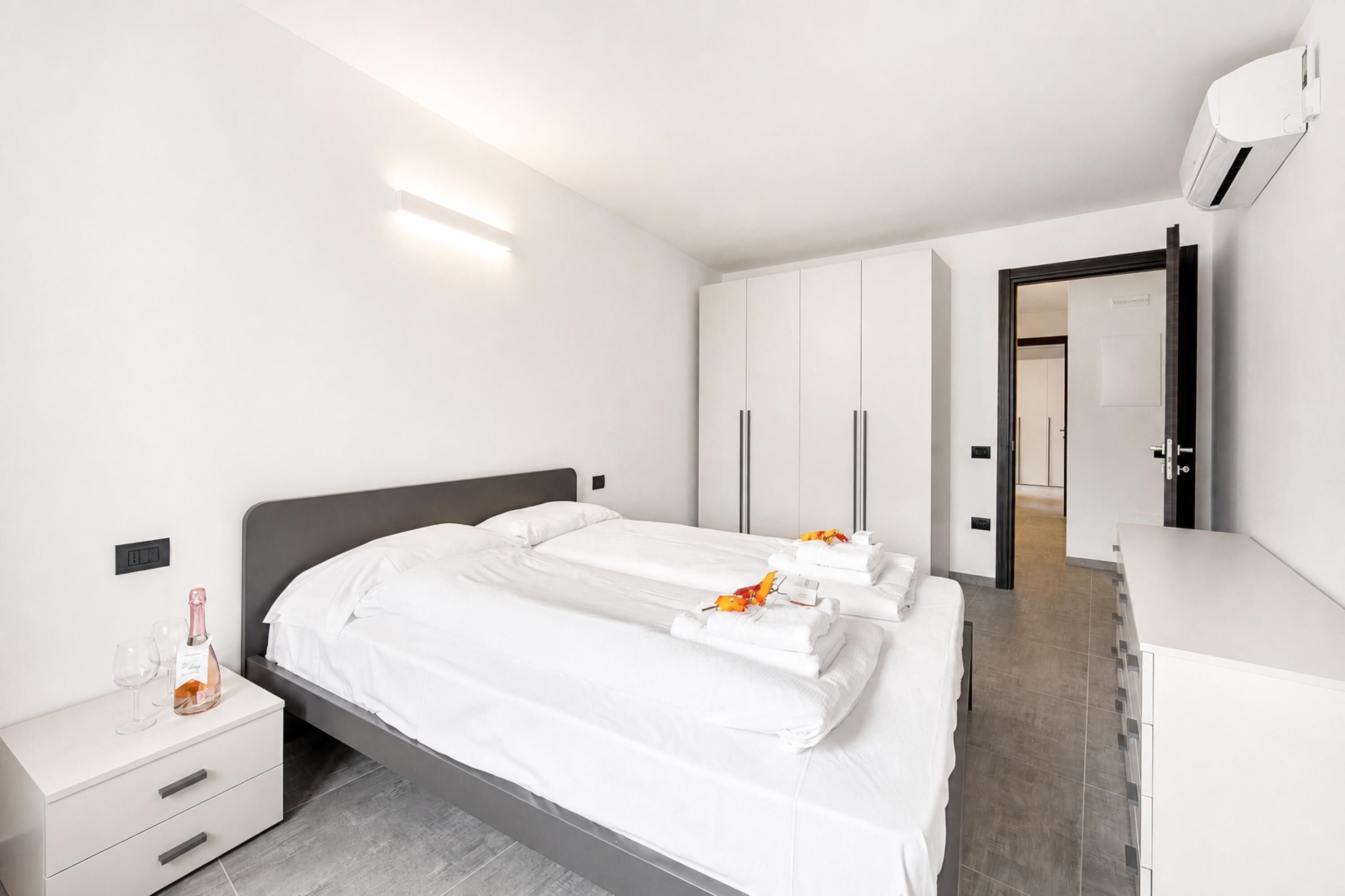A hotel room with a bed, a bedside table, a wardrobe, and a bathroom door.