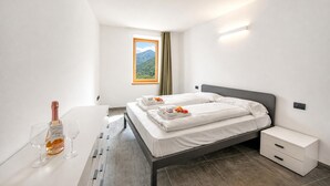 Une chambre d’hôtel moderne avec un lit, une table de chevet et une bouteille de champagne.