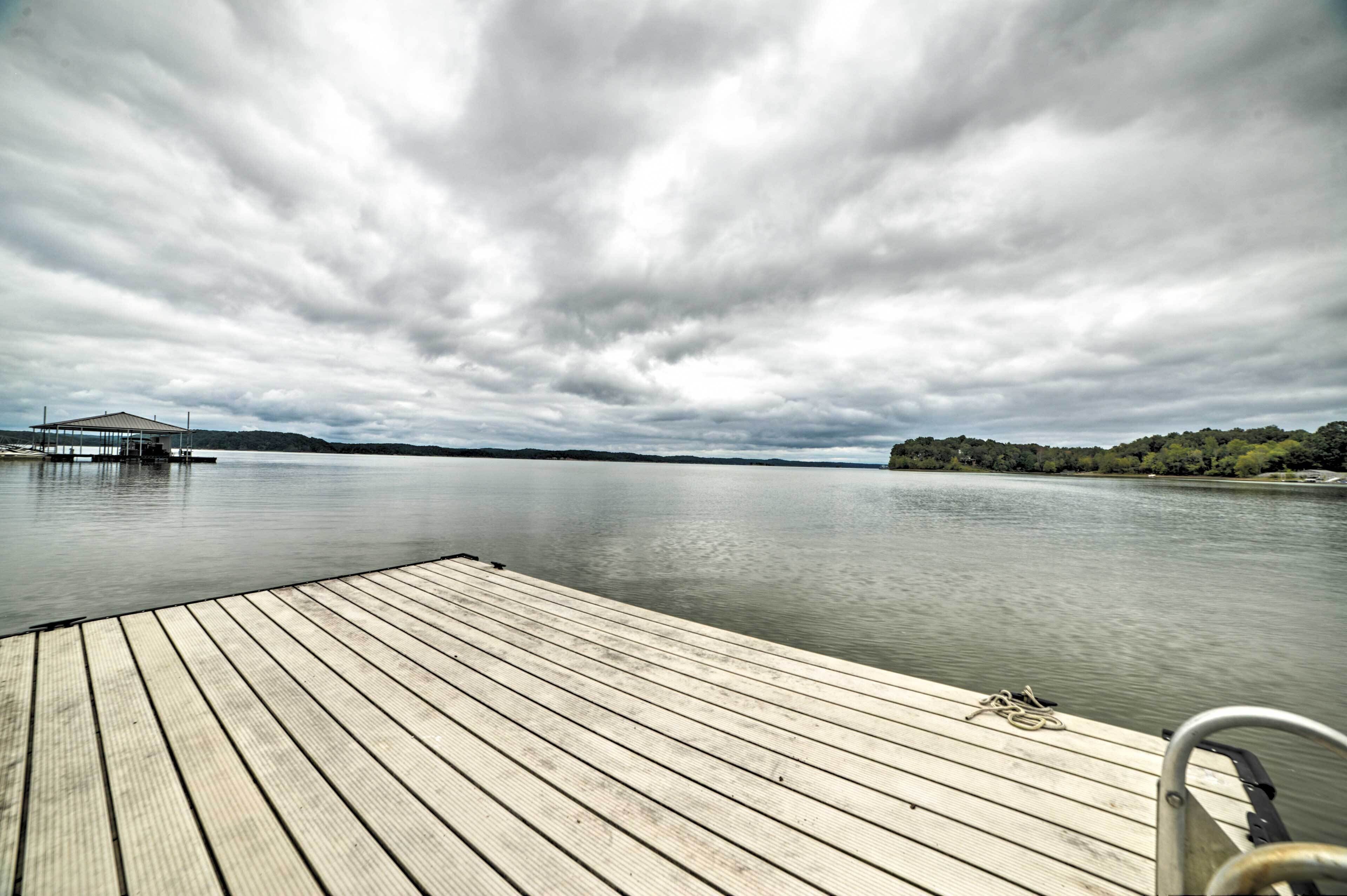 A wooden dock extending into a calm lake with a cloudy sky above.