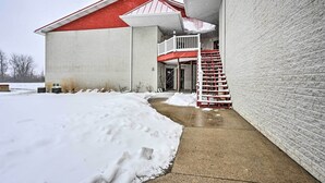 A building with a red roof and white walls, a concrete pathway, and a snow-covered ground. - Pigeon Retreat w/ Community Pool & Hot Tub! (Pigeon)