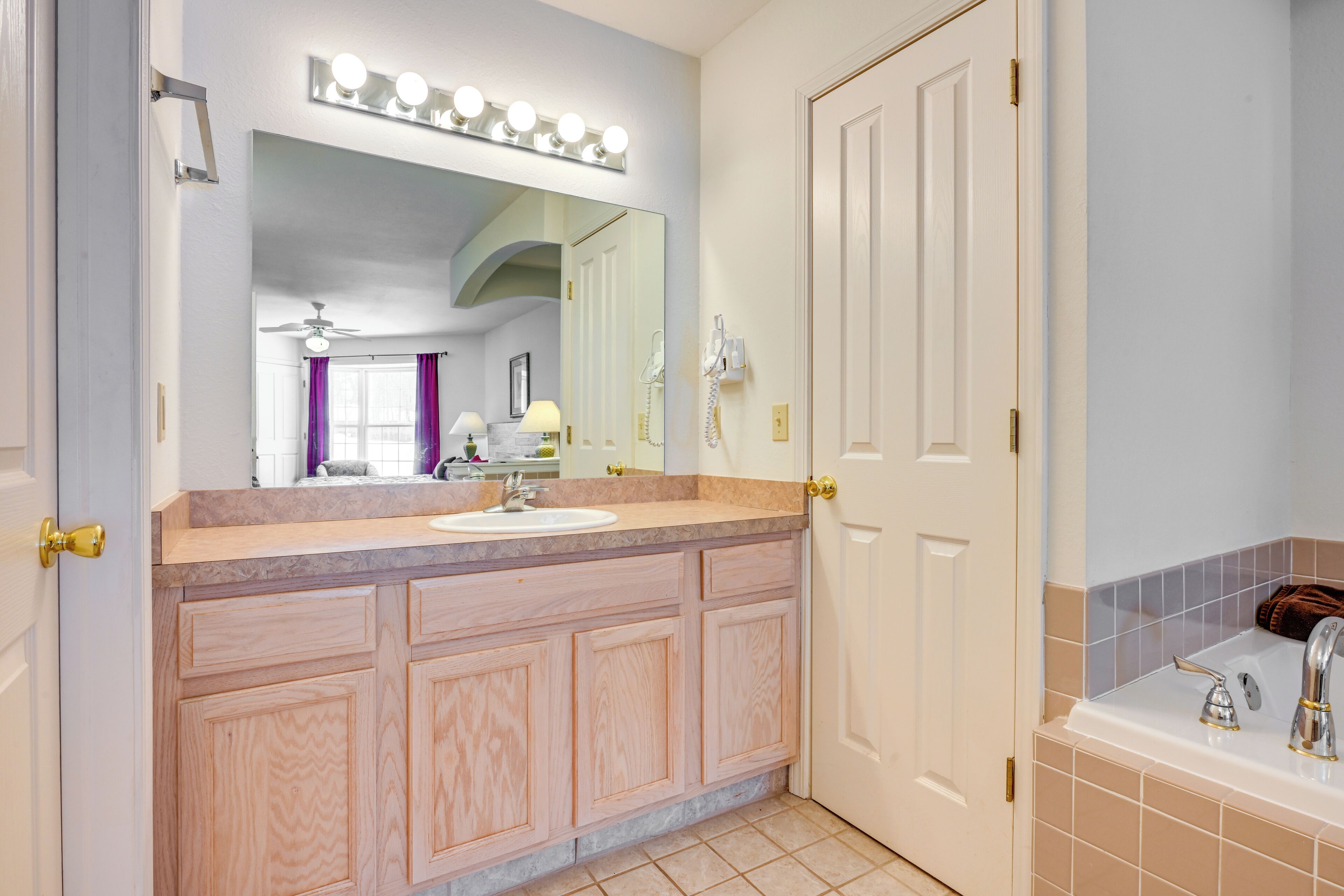 A bathroom with a vanity, sink, mirror, and a shower area.