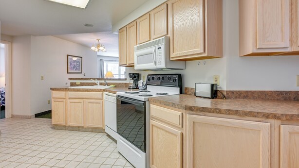 A kitchen with wooden cabinets, a white stove, and a microwave. - Pigeon Retreat w/ Community Pool & Hot Tub! (Pigeon)