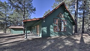 Une cabane en bois peinte en vert, avec un toit en pente, une véranda couverte et un petit abri attenant.