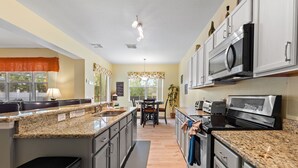 A modern kitchen with granite countertops, stainless steel appliances, and a central island. - Greenview Bliss By Shine Villas #031 5 Bedroom Villa (Davenport)