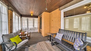 A cozy room with a wooden ceiling, a brick wall, and a large window. There is a bench with pillows and a small table with chairs. - Classy Colonial House w/ Furnished Sunroom! (North Lima)