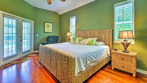 Une chambre avec un grand lit, un ventilateur de plafond et une fenêtre avec des stores.