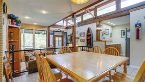 A spacious dining area with a large wooden table and chairs, surrounded by windows and a view of the outdoors. - Deck & Gas Grill: Riverfront Mcqueeney Duplex (McQueeney)