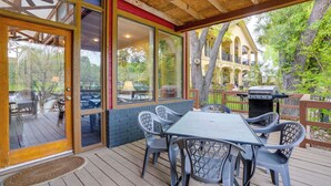 An outdoor patio with a table and chairs, a grill, and a view of a building with arches. - Deck & Gas Grill: Riverfront Mcqueeney Duplex (McQueeney)
