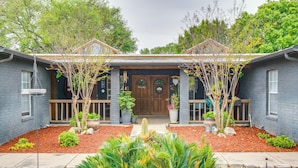A two-story house with a front porch, a wooden door, and a small garden with various plants and a cactus. - Deck & Gas Grill: Riverfront Mcqueeney Duplex (McQueeney)