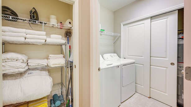 A laundry room with stacked towels, a washing machine, and a dryer. - Chic Country Club Condo With Pool Access! (Naples)