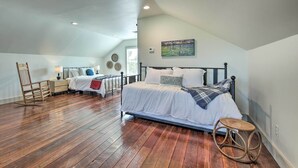 Quarto com uma cama grande, uma cadeira de balanço e um banquinho.