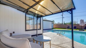 A covered outdoor seating area with a pool, wicker furniture, and a view of the pool.