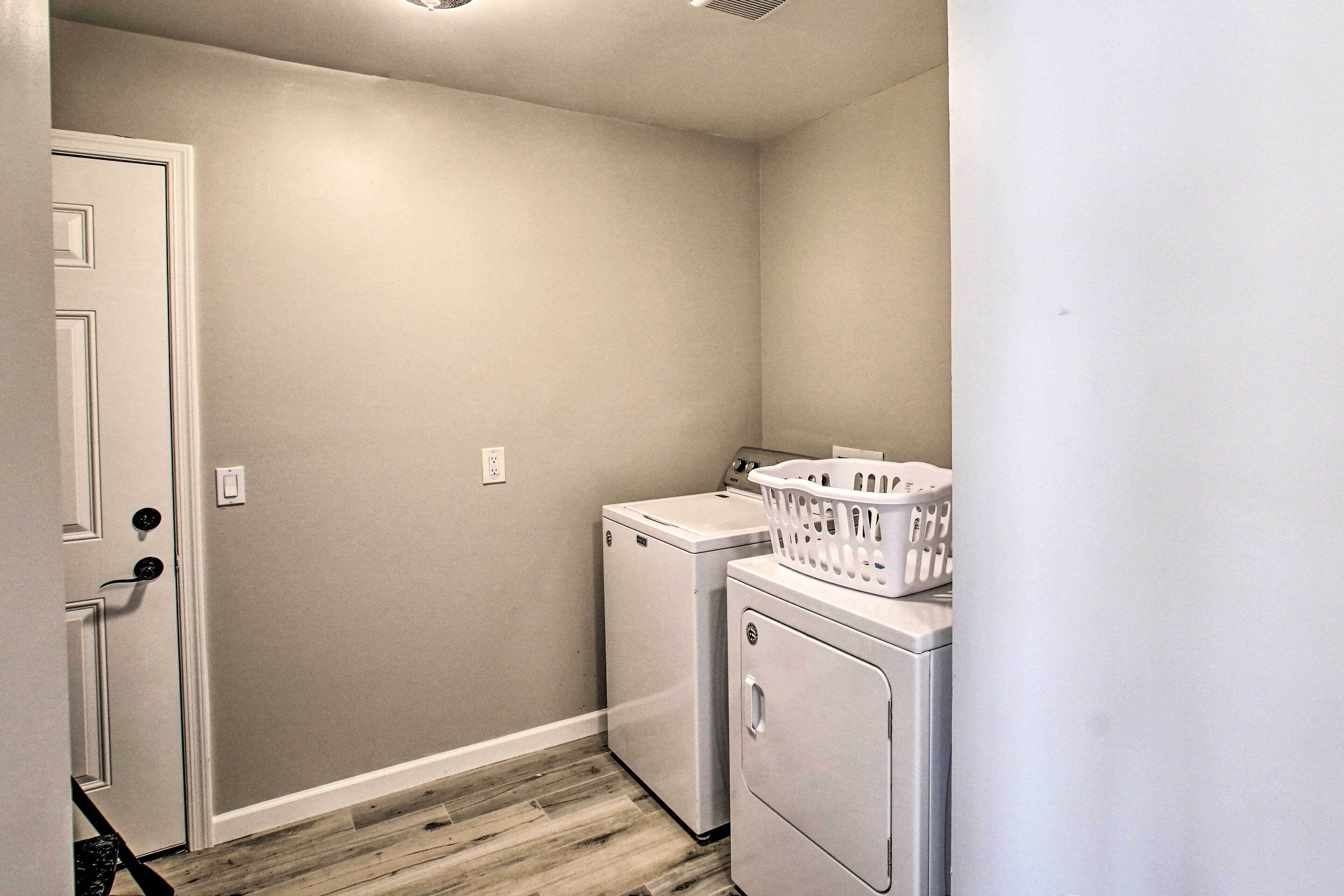 A laundry room with a washing machine, dryer, and a basket on the dryer.