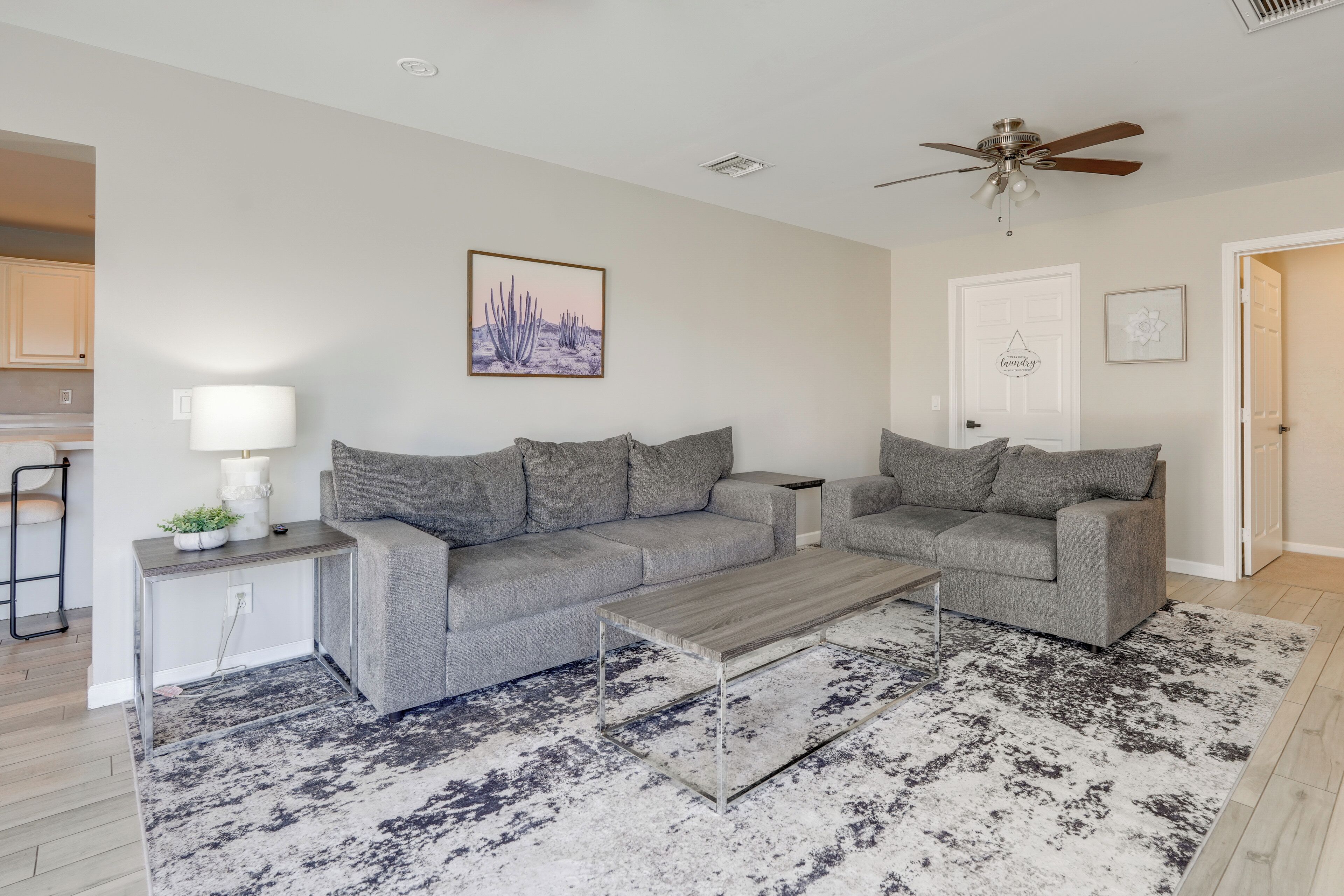 A modern living room with two grey sofas, a coffee table, and a patterned rug.