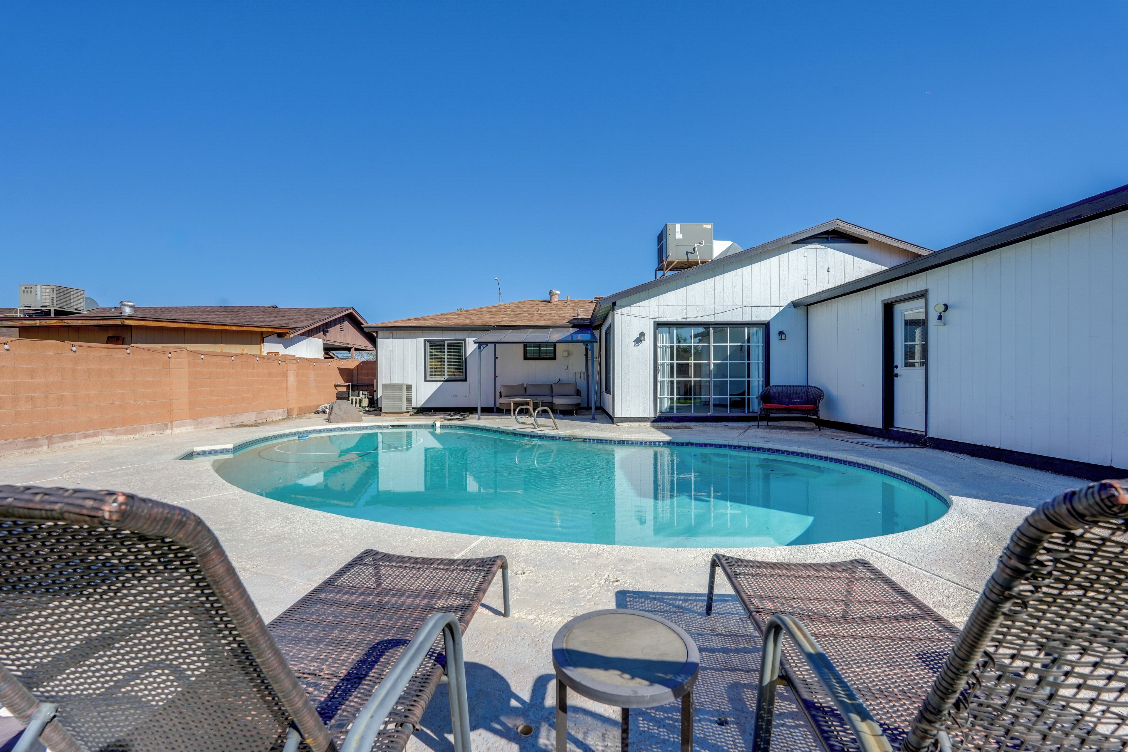 Une piscine sur le toit, dotée de chaises longues et d’une petite table, le tout entouré d’un bâtiment blanc aux grandes fenêtres.
