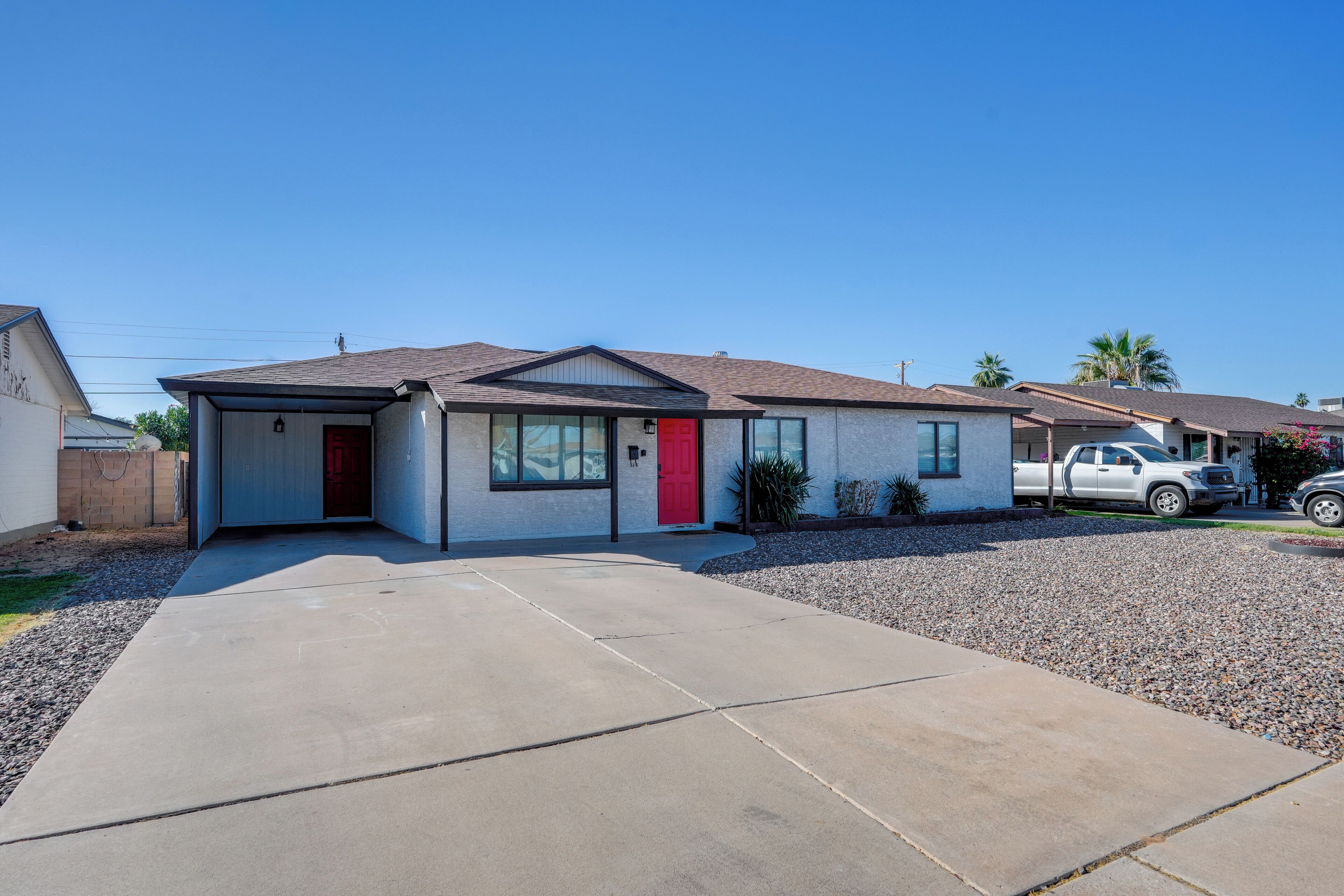 A single-story house with a red door, a garage, and a driveway.