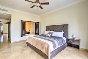 A bedroom with a large bed, a nightstand, a ceiling fan, and a mirror on the wall. - Walk to Beach: Modern Cabo Condo w/ Balcony! (Cabo San Lucas)