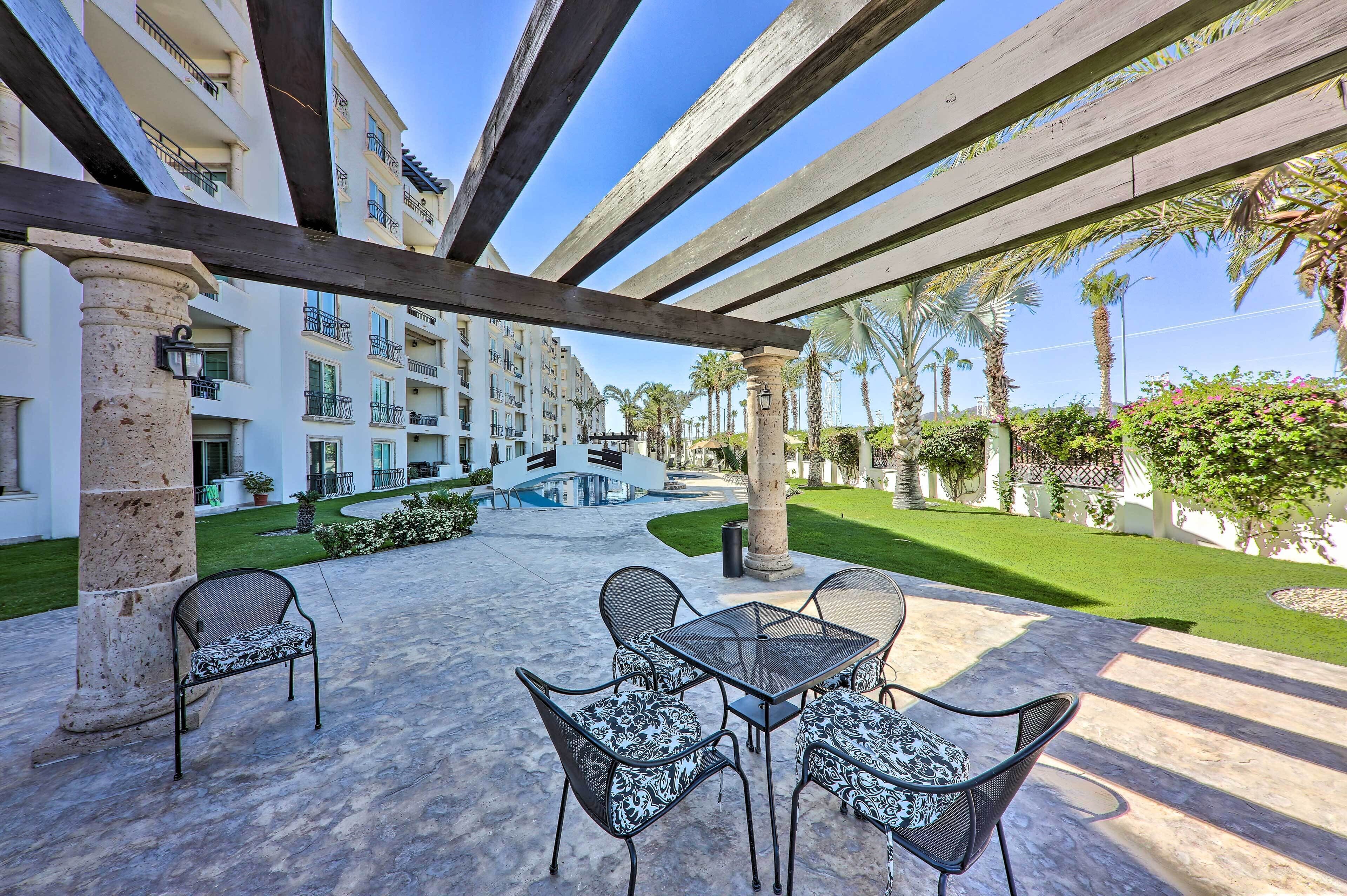 An outdoor patio with a pool, surrounded by a well-maintained lawn and palm trees.