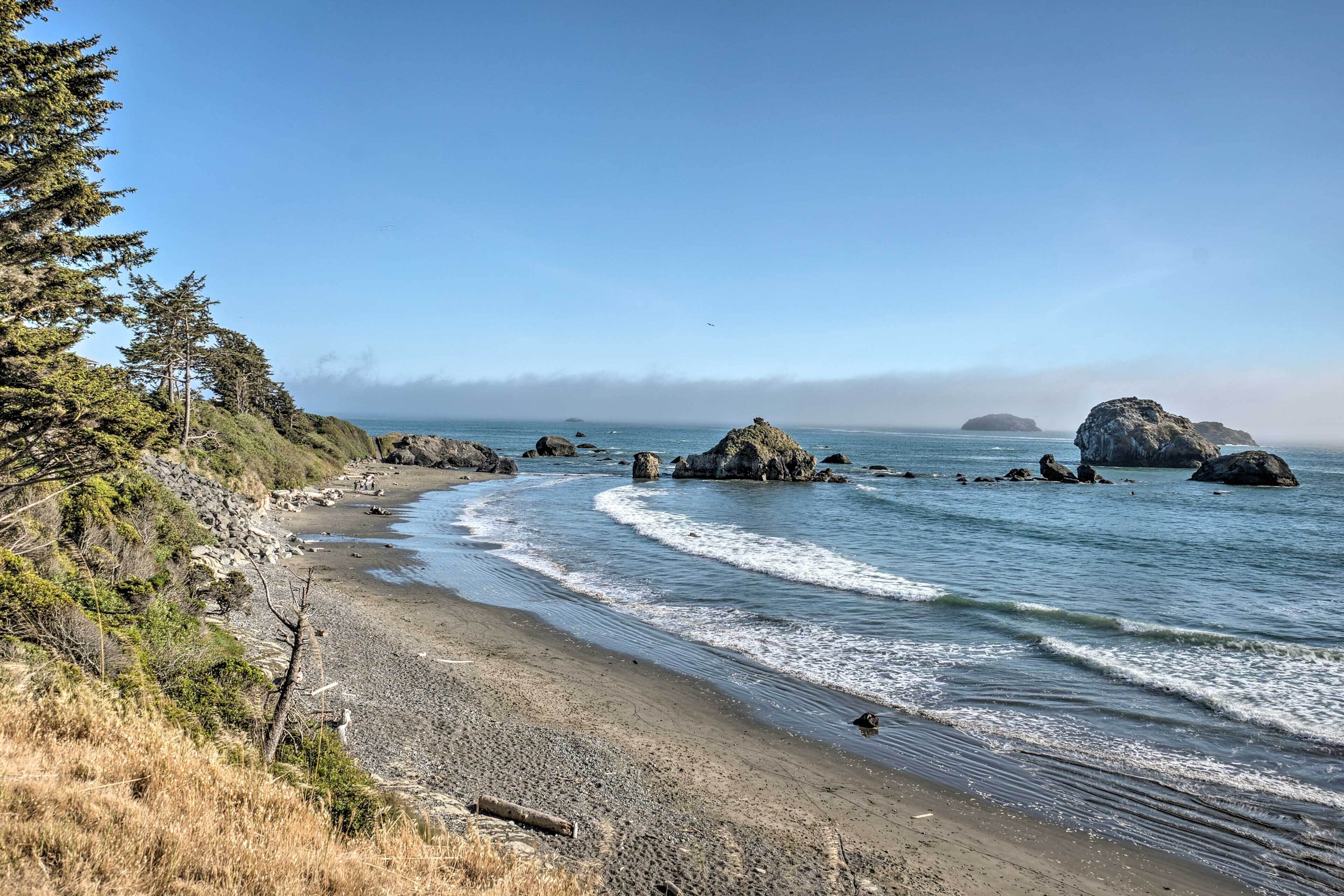 Une plage côtière avec des affleurements rocheux et un ciel dégagé.