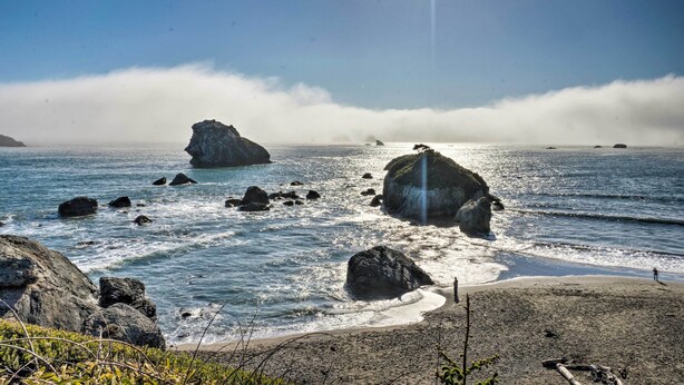 Una playa con rocas grandes y olas.