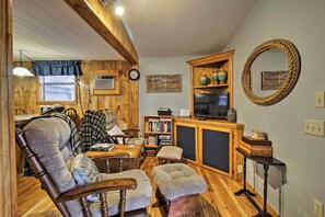 Un intérieur de chalet chaleureux avec des murs en bois, une cheminée, une bibliothèque et un téléviseur.