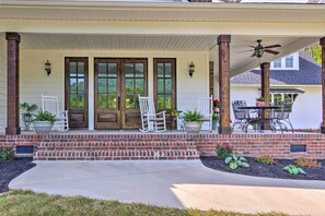 A covered porch with a brick entrance, two white rocking chairs, and a table with chairs. - Near Parks, Trails & Lakes: Quaint Landrum Escape! (Landrum)