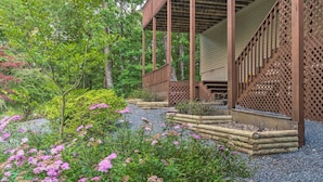 A wooden structure with a lattice design, surrounded by a garden with gravel paths and pink flowering plants. - Deck w/ Bbq: Hot Springs Village Apt! (Hot Springs Village)