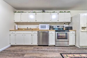 A kitchen with white cabinets, a stainless steel dishwasher, a microwave, a coffee maker, and an oven. - Deck w/ Bbq: Hot Springs Village Apt! (Hot Springs Village)