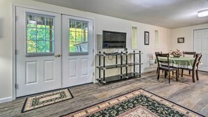 A dining area with a table set for four, a television mounted above it, and a door with a window. - Deck w/ Bbq: Hot Springs Village Apt! (Hot Springs Village)