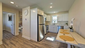 Une cuisine moderne avec des meubles blancs, des appareils en acier inoxydable et une table à manger en bois agrémentée de sets de table.