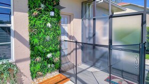 A modern house with a green vertical garden, a glass door, and a welcome mat. - Bright & Sunny Riverview Oasis w/ Pool & Pond (Riverview)