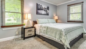 A bedroom with a bed, bedside lamps, a nightstand, a wall-mounted picture, and a window with blinds. - Indianapolis Vacation Rental ~ 8 Mi to Downtown! (Indianapolis)