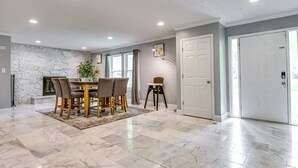A spacious room with a marble floor, a dining table with chairs, a fireplace, and a door with a view. - Indianapolis Vacation Rental ~ 8 Mi to Downtown! (Indianapolis)