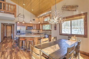 A spacious kitchen with wooden cabinets, a large island, and a chandelier.