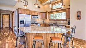 A spacious kitchen with wooden cabinets, a large island with stools, stainless steel appliances, and pendant lighting. - Rustic Mountain Sanctuary on 2+ Acres w/ Deck! (Alma)
