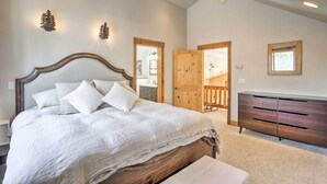 A bedroom with a large bed, wooden headboard, and a ceiling fan. There is a dresser and a door leading to another room. - Rustic Mountain Sanctuary on 2+ Acres w/ Deck! (Alma)