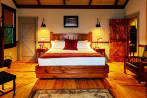 Um quarto espaçoso com uma cama de madeira grande, duas mesas de cabeceira com luminárias, um banco de madeira e uma porta de celeiro rústica.